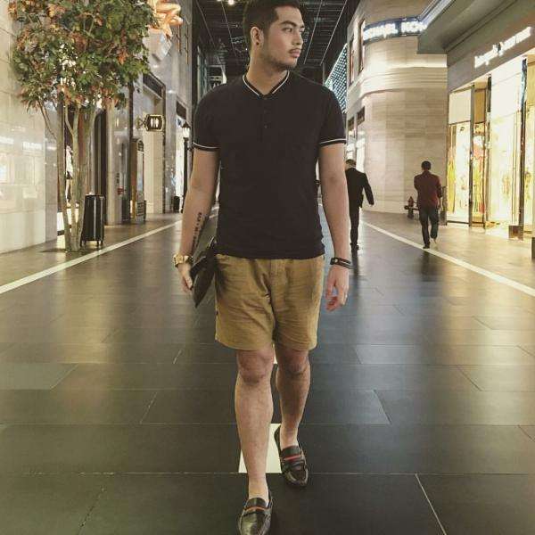 A young man wears shorts and a dark top.