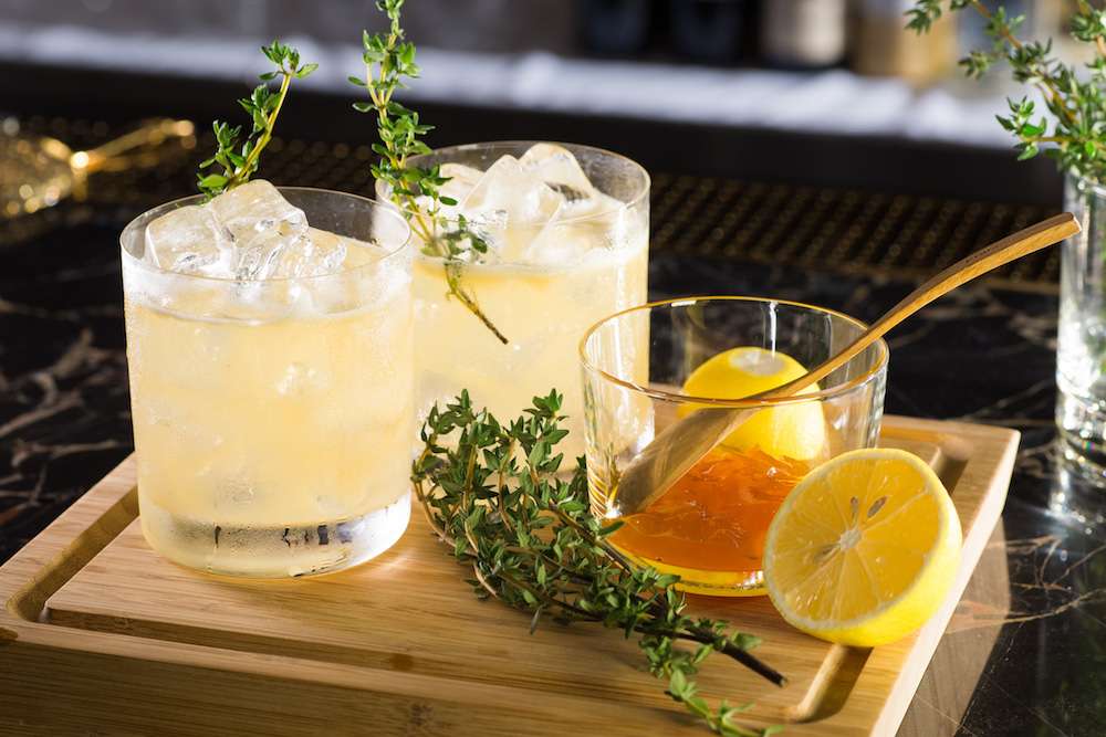 Ingredients for a whiskey-based cocktail displayed on a wooden cutting board. 