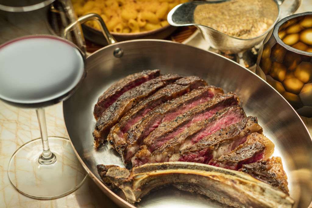 Sliced rib eye steak with a glass of red wine