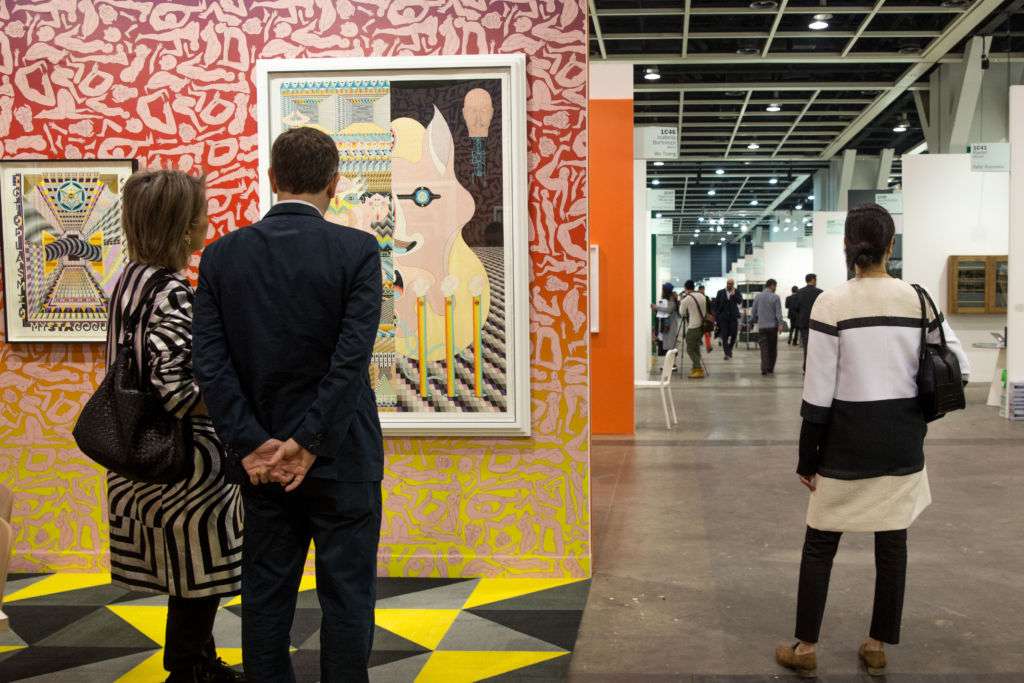 A man and woman look at a painting at Art Basel art show in Hong Kong. 