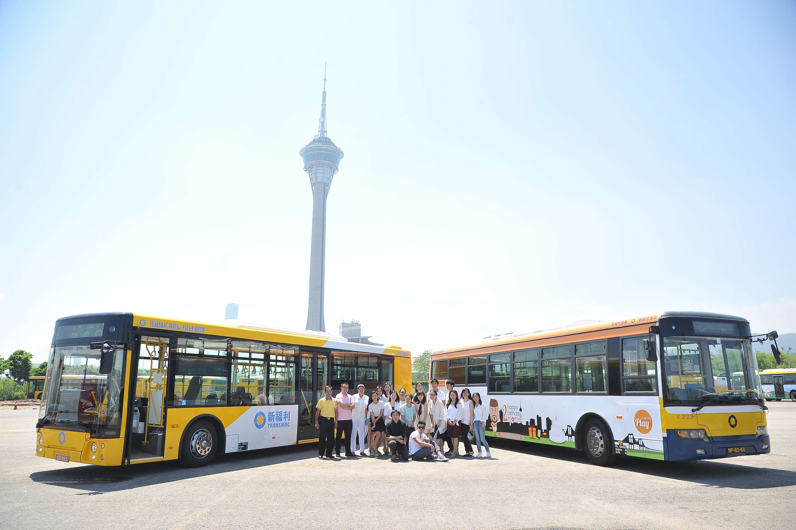 Group photo in front of two buses with Macau Tower in the back