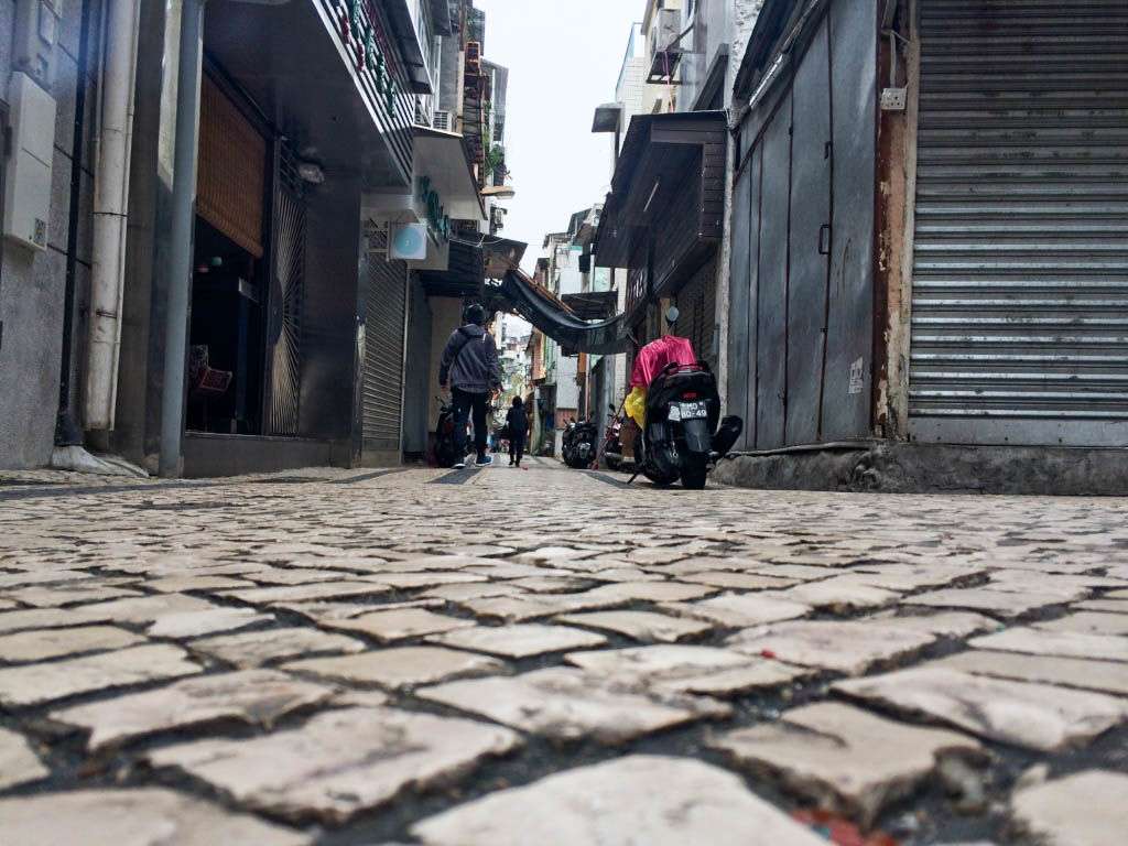 A small street in Macau with people walking. 