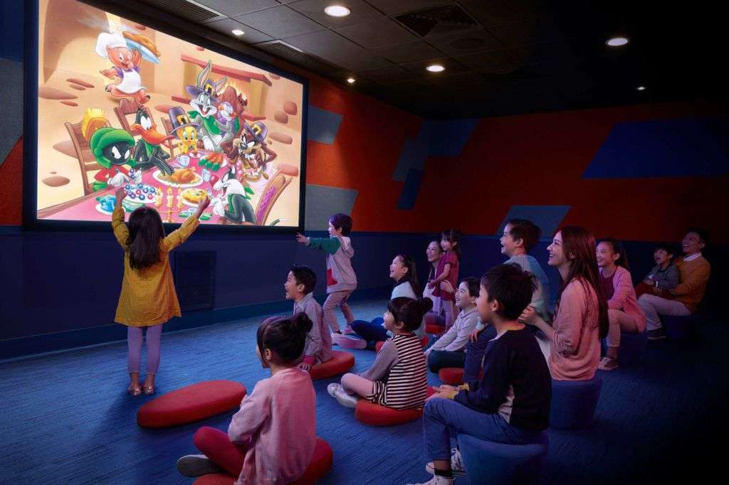 Children sitting on floor watching a cartoon movie on a big screen