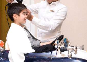 A kid gets hair blow dried by hairdresser at JW Marriot Hair Salon
