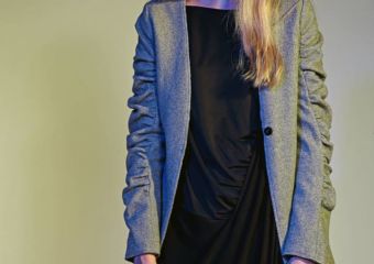 A girl wears a long grey coat and black dress