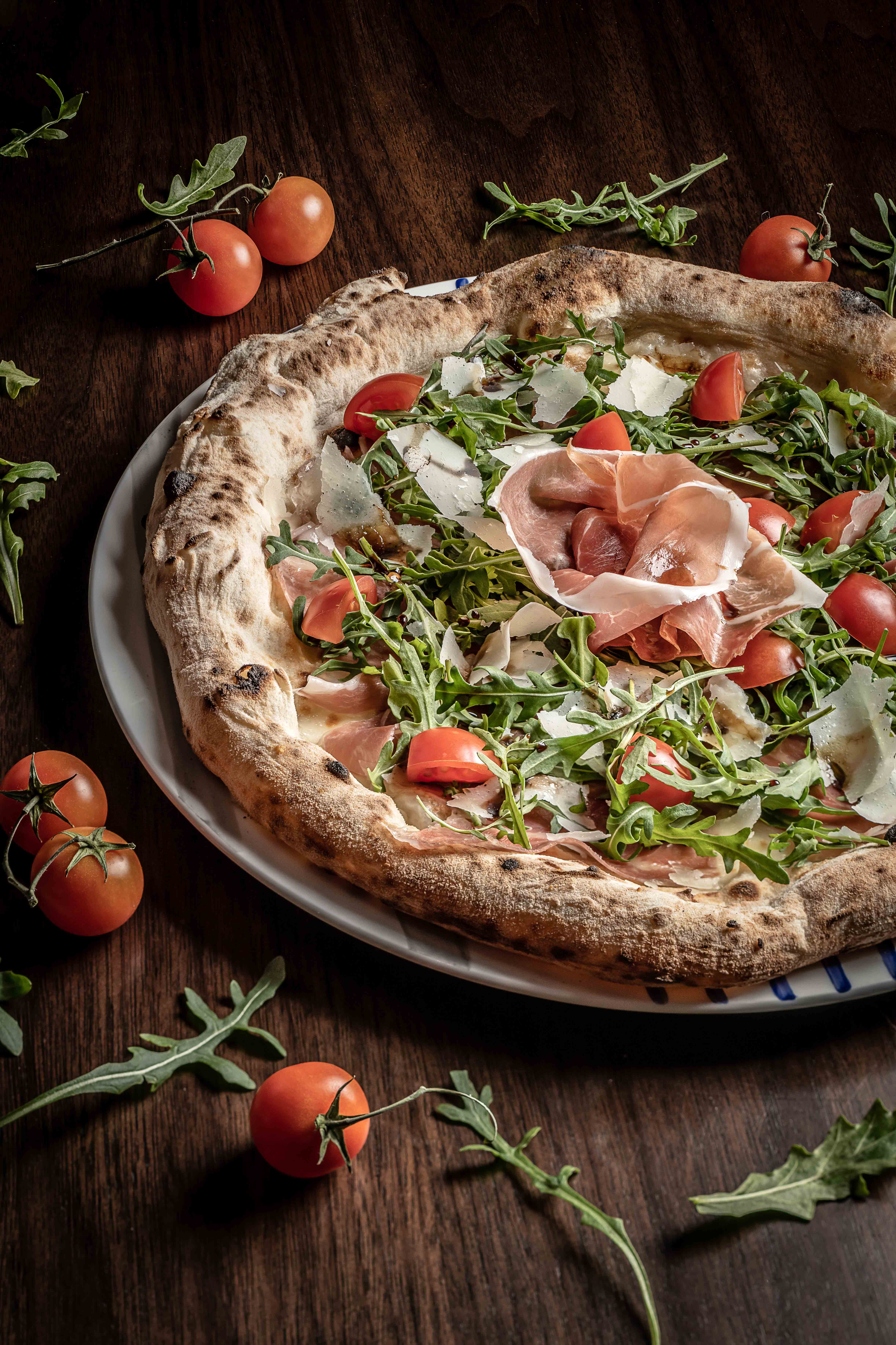 Casa Don Alfonso Pizza with mozzarella, Parma ham wild arugula, cherry tomatoes, parmesan flakes and aged Modena balsamic vinegar