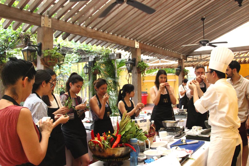 Nine students gathered around Chef Pairoj for Thai cooking class at Naam restaurant in Macau.