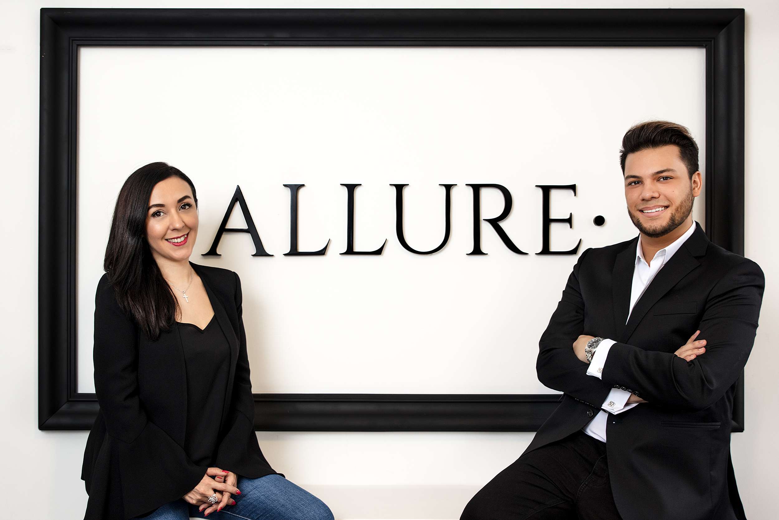 Maria Garcia and Miguel Costa posing at Allure's signage