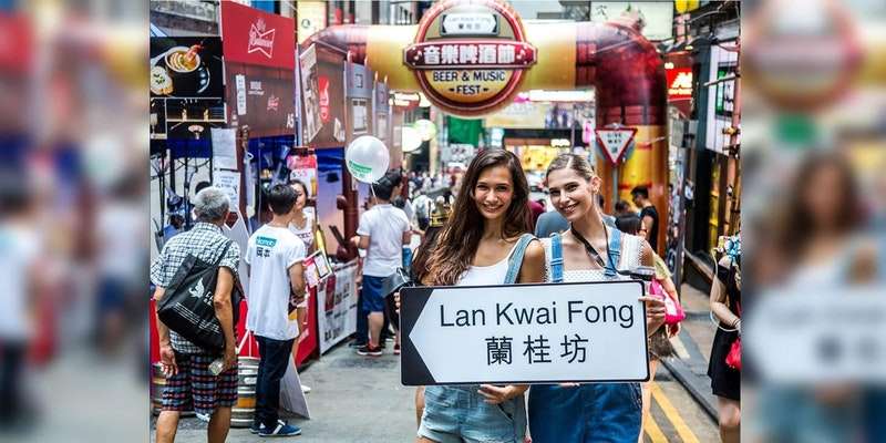 Two girls holding street sign at Lan Kwai Fong Beer and Music Fest 2017 in Hong Kong. 