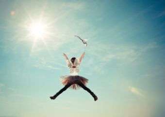 Little girl jumping in the sun with tutu and butterfly wings