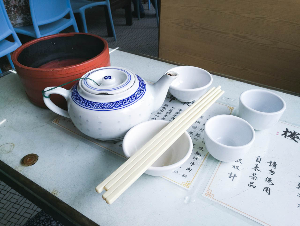 Teapot, bowls, and chopsticks on table in Long Wah teahouse in Macau.