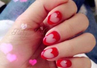 Hand with hearts negatively imprinted on nails. The heart is empty space, the surrounding is red.