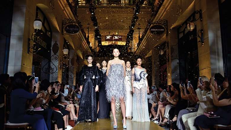 A group of female models walk down a fashion show runway.