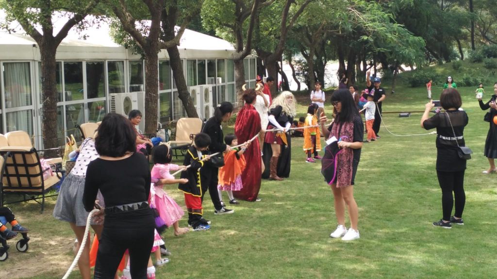 Children and adults playing Halloween party games on the lawn of the Grand Coloane Resort in Macau.