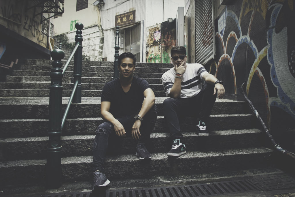 Two young men sitting on steps on a small street in Macau
