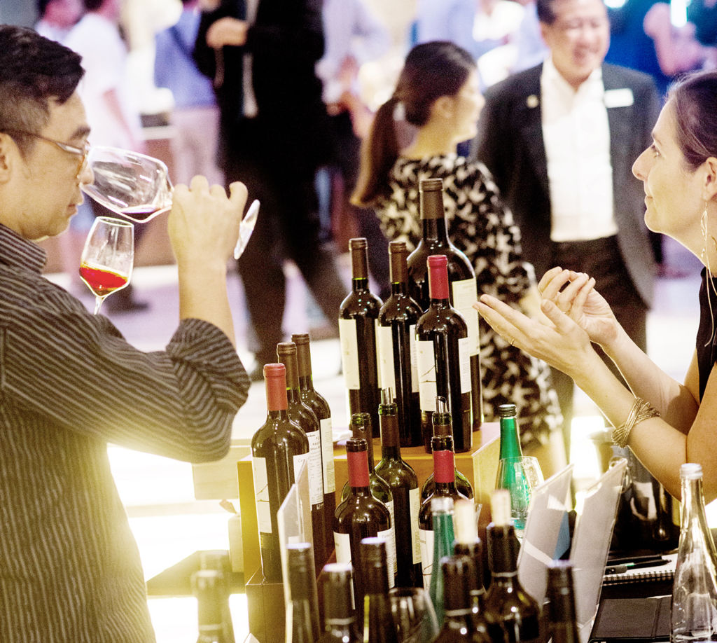 A man and a woman taste wine and while discussing the wine.