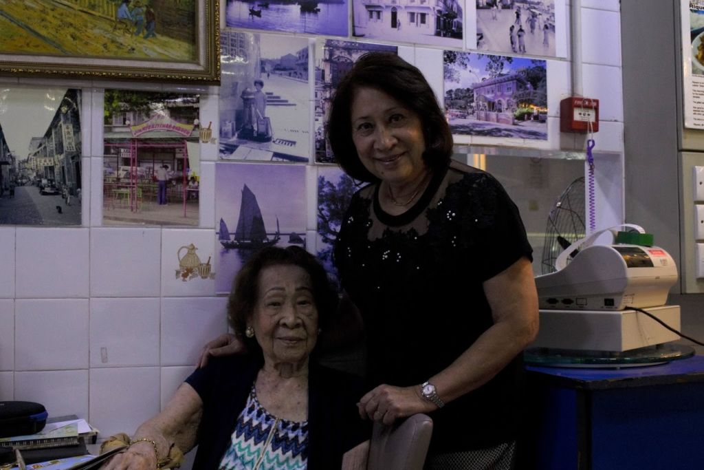 Two older women pose at a restaurant.