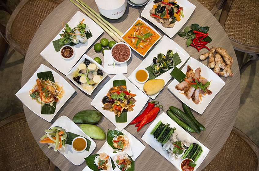 A large selection of Thai dishes arranged on a table and viewed from above.