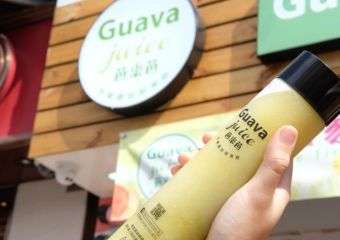Someone holding a bottle of juice from a Guava Juice cafe in Macau.