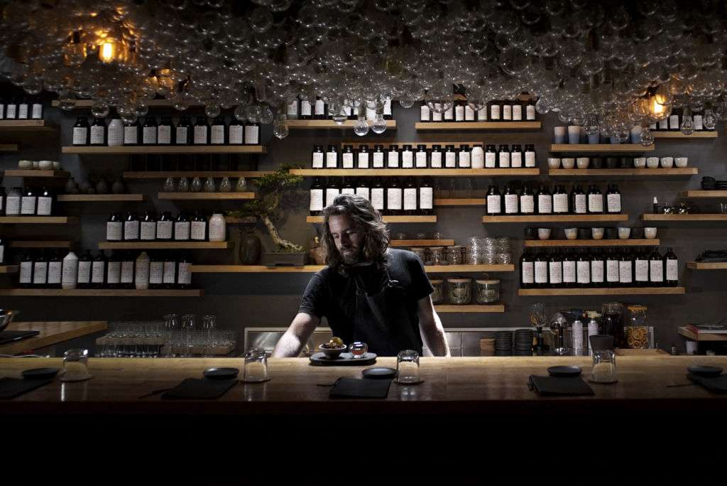 A man behind a bar making a drink.