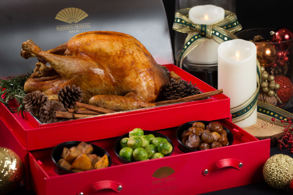 A roasted turkey with side dishes served in a red box with drawers. 