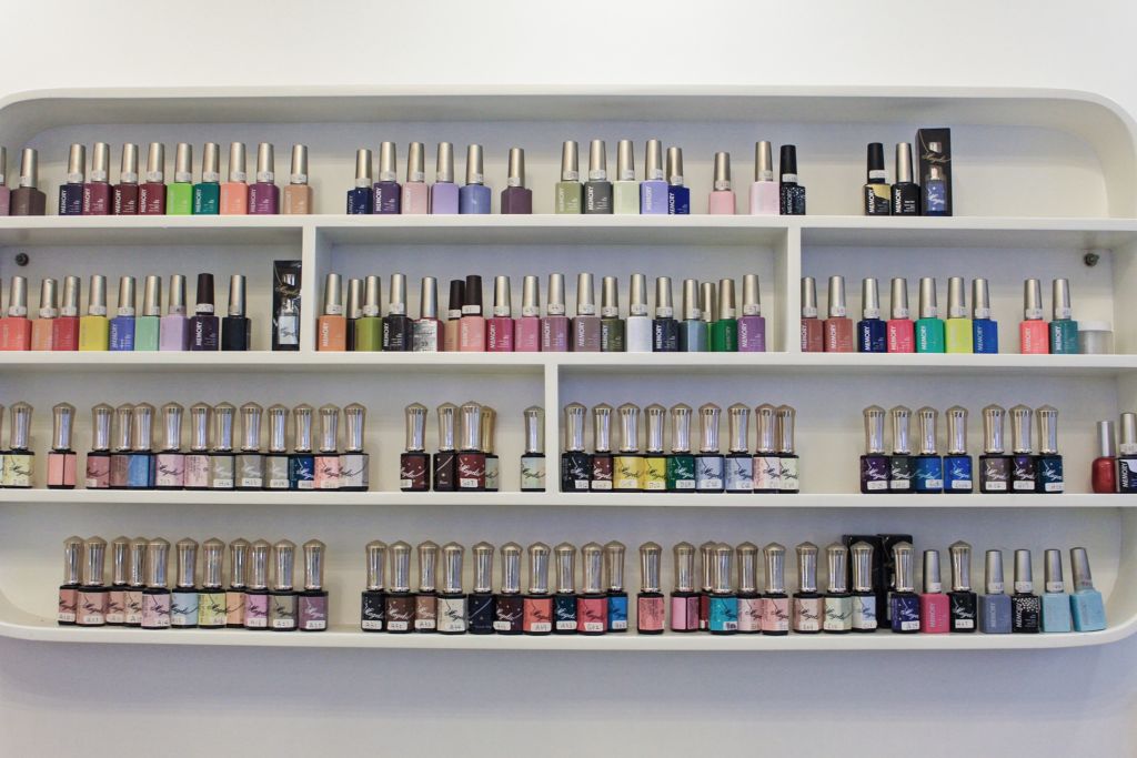 4 levels of shelves displaying various nail polishes and other nail-related supplies. 