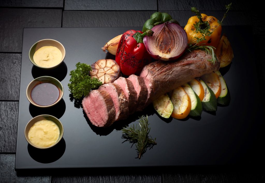 A beautiful cut of pork sliced and served on a black lacquer presentation tray.