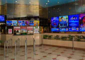 Wide shot of the ticketing counter and the screens showing movie posters at Cineteatro Macau