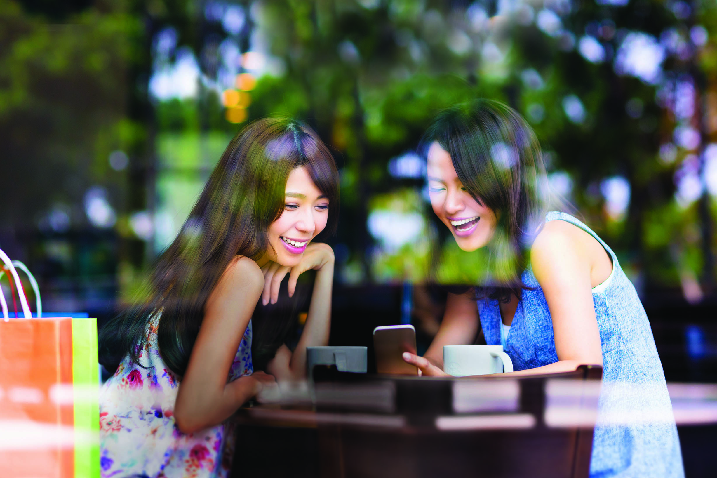 happy young woman looking at phone in coffee shop